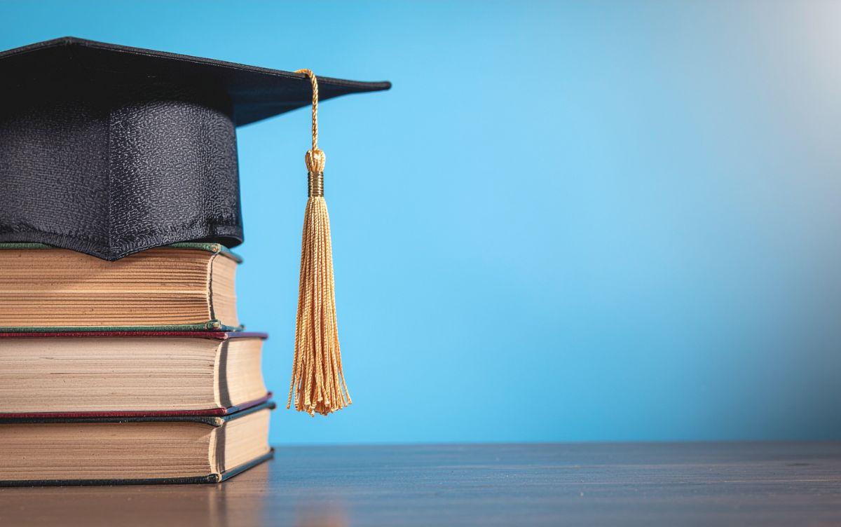 Cappello di laurea con nappina dorata sopra una pila di libri Cappello di laurea con nappina dorata sopra una pila di libri