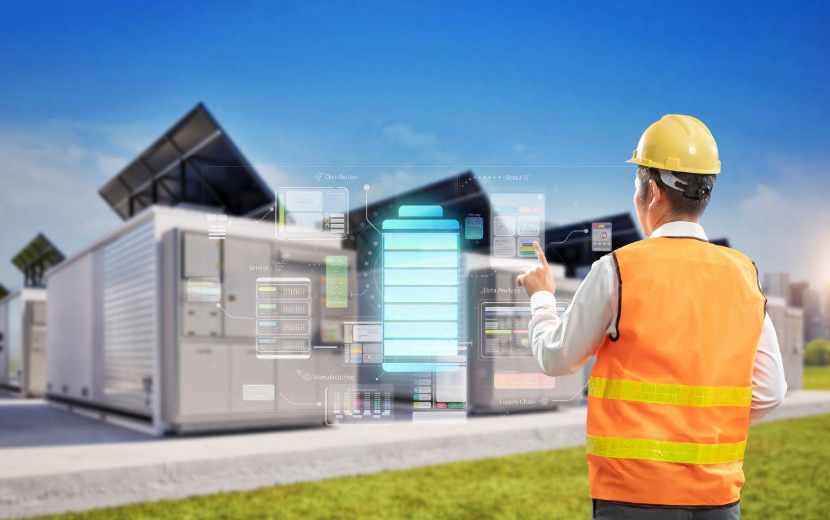 Tecnico con casco progetta impianti energetici con interfaccia digitale, batterie e pannelli solari